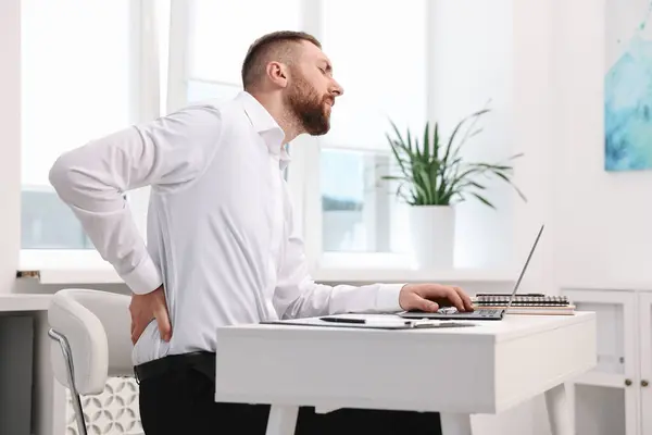 stock image Man suffering from back pain in office. Symptom of poor posture