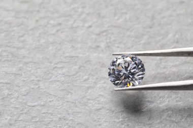 Işık desenli arka planda parlak pırlantalı cımbızlar, yakın plan. Metin için boşluk