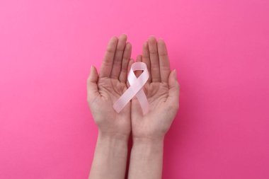 Pembe arka planda farkındalık kurdelesi olan kadın, üst görünüm