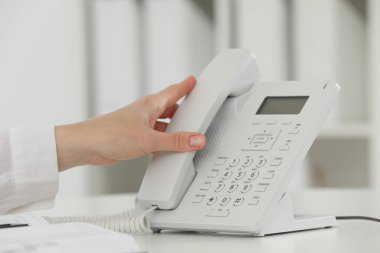 Assistant taking telephone handset at white table, closeup