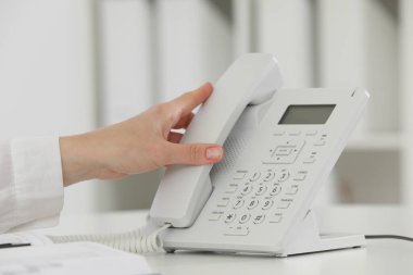 Assistant taking telephone handset at white table, closeup clipart