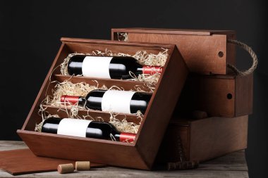 Ahşap masanın üzerinde şarap şişeleri olan bir kutu.