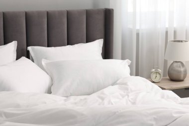 Yatakta bir sürü yumuşak yastık ve evdeki komodinin yanında