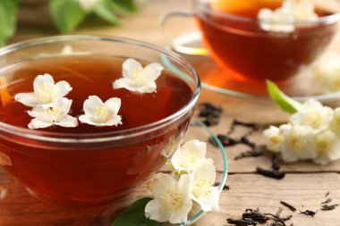 Sıcak yasemin çayı fincanda ve çiçekler ahşap masada, yakın plan.