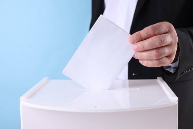 Adam oyunu açık mavi arkaplana karşı sandığa koyuyor.