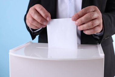 Adam oyunu açık mavi arkaplana karşı sandığa koyuyor.