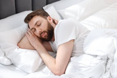 Yakışıklı genç adam, sabahları yatakta uyuyor.