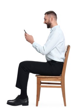 Sandalyeye oturup beyaz arka plana karşı akıllı telefon kullanan iyi duruşu olan adam.