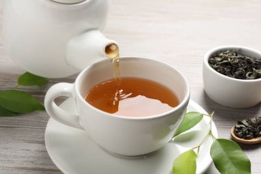 Gri ahşap masada serinletici yeşil çayı fincana dök, kapat.