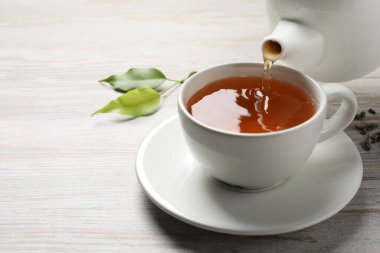 Gri ahşap masada taze yeşil çayı bardağa dolduruyor, yakın plan. Metin için boşluk