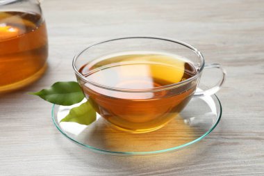 Yeşil çayı fincanda tazeliyor ve açık ahşap masada yapraklar, yakın plan