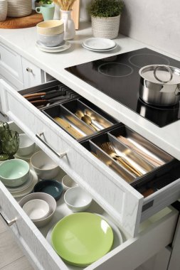 Mutfaktaki çekmecelerde seramik bulaşık takımı ve çatal bıçak takımı.