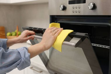 Kadın mutfakta, closeup bez ile elektrikli fırın Temizleme