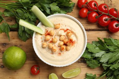 Lezzetli humus, kasede nohut ve ahşap masada taze ürünler.