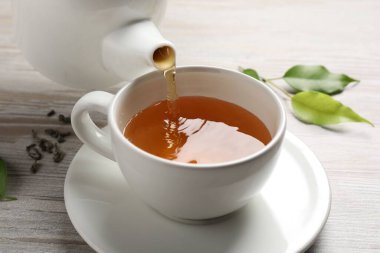 Gri ahşap masada serinletici yeşil çayı fincana dök, kapat.