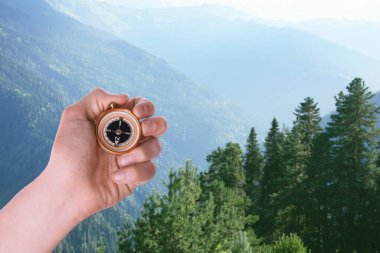 Dağlarda pusula kullanan bir adam, yakın plan. Seyrüsefer aracı