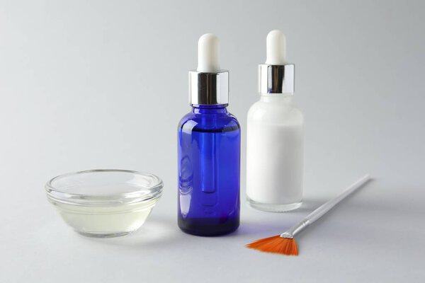 Bottles of chemical peel, bowl with liquid and brush on light background, closeup. Peeling procedure
