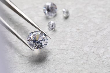 Işık desenli arka planda parlak elmasları olan cımbızlar, yakın plan. Metin için boşluk