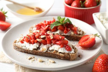Ricotta peyniri, doğranmış çilek ve beyaz ahşap masada nane şekeri, yakın plan.