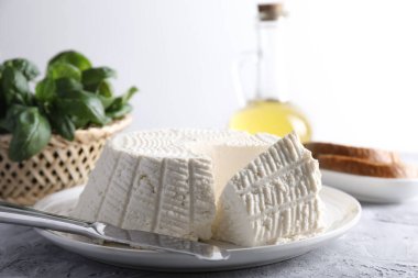 Lezzetli ricotta (krem peynir) ve gri desenli masada bıçak, yakın plan.