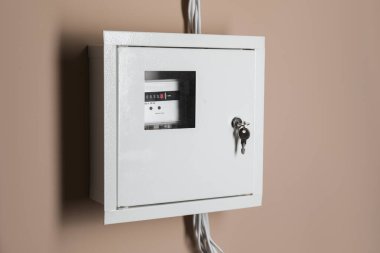 Bej duvarda sigorta kutusundaki elektrik sayacı. Enerji ölçüm aygıtı
