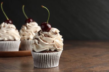Tahta masada kremalı ve kirazlı enfes kekler, yakın plan. Metin için boşluk
