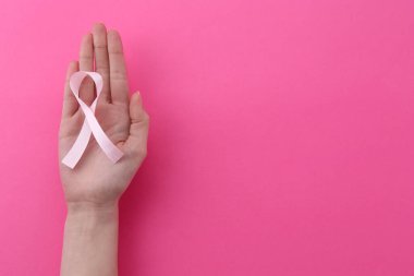 Pembe arka planda farkındalık kurdelesi olan bir kadın. Metin için boşluk