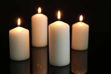 Birçok yanan mum ayna yüzeyinde siyah arkaplana karşı