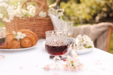 Güzel bahar çiçekleri, şarap ve kruvasanlarla süslü masa.