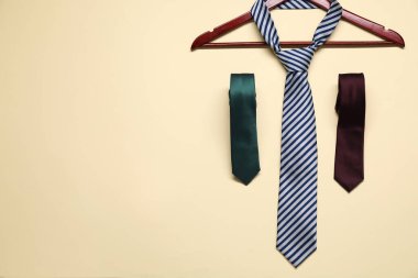 Hanger and neckties on beige background, flat lay. Space for text