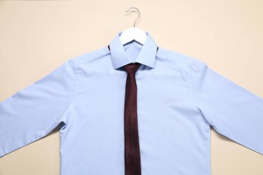 Bej arka planda gömlek ve kravat askısı, üst görünüm