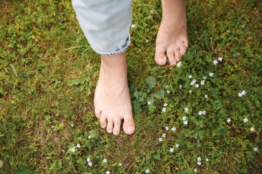 Woman walking barefoot on green grass outdoors, top view