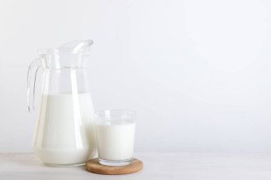 Sürahi ve bir bardak taze süt ahşap masada, mesaj için yer var.