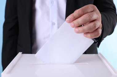 Adam oyunu açık mavi arkaplana karşı sandığa koyuyor.