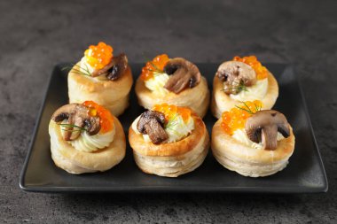 Krem peynirli lezzetli puf böreği, kırmızı havyar, mantar ve dereotu gri masada.