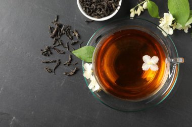 Cam bardakta Aromatik yasemin çayı, gri masada çiçekler ve kuru yapraklar, üst manzara