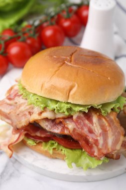 Pastırmalı lezzetli hamburger ve beyaz mermer masada domates.