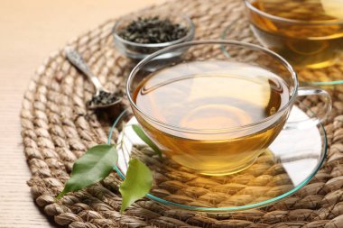 Yeşil çayı fincanda tazeleyen ve ahşap masada yapraklar, yakın plan