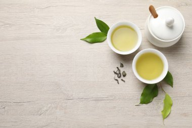 Yeşil çayı fincanlarda, şeker kasesinde ve yaprakları ahşap masada, düz bir şekilde serinletiyor. Metin için boşluk