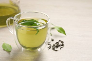 Yeşil çayı fincanda tazelemek, çaydanlık ve yaprakları ahşap masada, yakın plan. Metin için boşluk