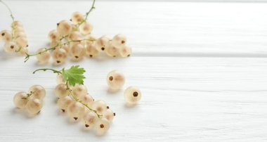 Taze kuşüzümü ve yeşil yaprak beyaz ahşap masada, yakın plan. Metin için boşluk