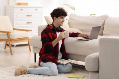 Evde dizüstü bilgisayarla çalışan içki içen bir genç. Uzak görev