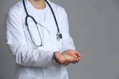 Doktor gri arka planda bir şey tutuyor, yakın plan. Metin için boşluk