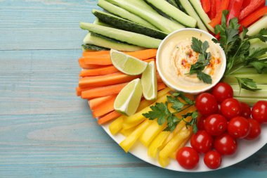 Lezzetli ev yapımı humus, farklı sebzelerle servis edilir açık mavi ahşap masa, üst manzara. Metin için boşluk