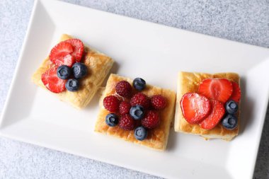 Açık gri masada böğürtlenli lezzetli puf börekler.
