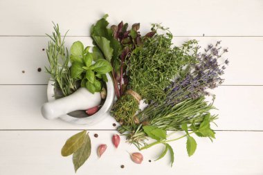 Farklı aromatik otlar, sarımsak, harç ve tokmak beyaz ahşap masa, üst görünüm