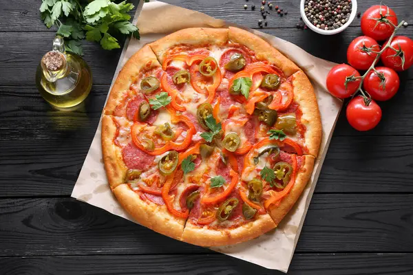 stock image Delicious pizza Diablo and ingredients on black wooden table, flat lay