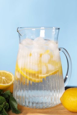 Açık mavi arka planda, tahta masada naneli taze limonata.