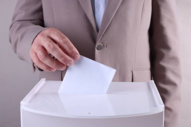 Adam oyunu açık gri arka plana karşı sandığa koyuyor, yakın plan.