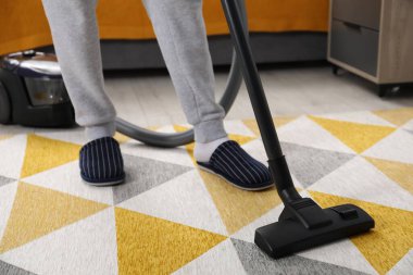 Man with vacuum cleaning carpet indoors, closeup clipart